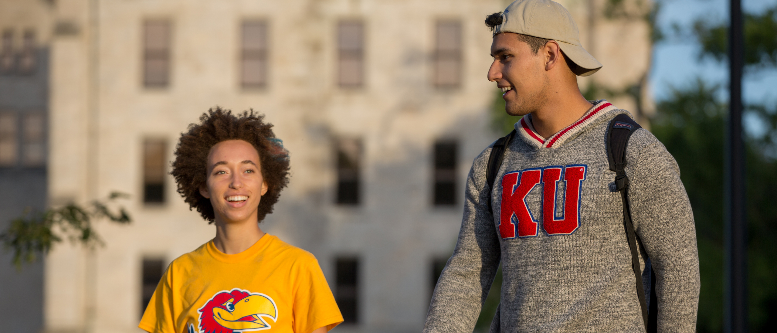 two students walking on campus in KU gear