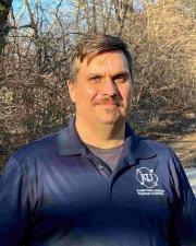 Photo of Lucas Everett in an blue KFRTI polo standing in front of a wooded area