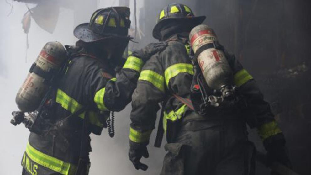 firefighters searching a smokey interior of a house